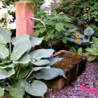 Gartengestaltung: Schattenpflanzung mit Hosta sieboldiana 'Blue Angel', Hortensien, Sandsteinbrunnen